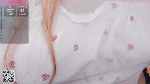 Media: Video of a woman with long, light pink hair wearing a sheer white blouse with heart patterns. A QR code is visible in the bottom left corner.