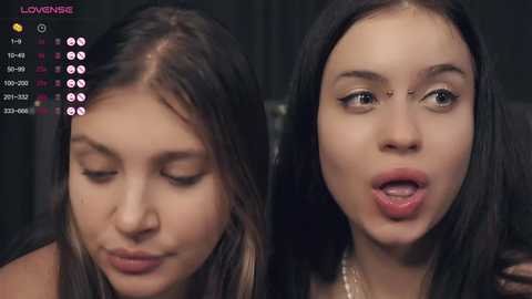 Media: A video juxtaposes two young women with fair skin, dark hair, and neutral expressions; the background is dark and indistinct.