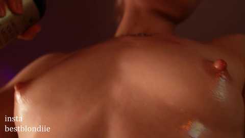 Media: A close-up video of a nude woman with light skin, small breasts, and visible nipples, viewed from behind, in a dimly lit room.