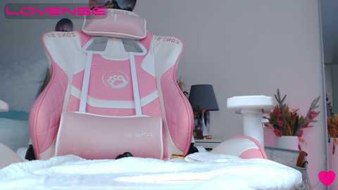 Media: Video of a pink gaming chair with white accents, a white laptop bag, and a white desk with a lamp, cat toys, and a cat statue.