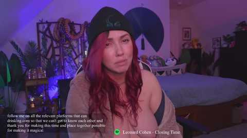 Media: A video of a young woman with long, wavy red hair, wearing a black beanie, light shirt, and black bra, in a dimly lit bedroom with purple lighting. Text overlays suggest a video game context.