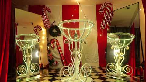 Media: A festive video depicts a Christmas-themed room with large, ornate glass candy dishes, red and white striped candy canes, a red curtain, and a black-and-white checkered floor.