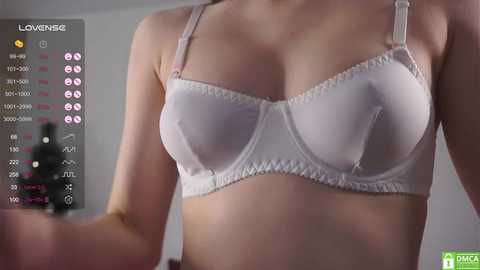 A close-up video of a woman wearing a white lace bra, with a digital health monitor displaying vital signs in the background.