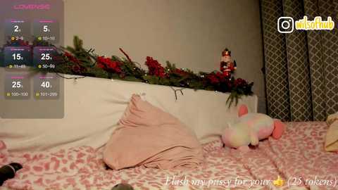 Video of a cozy bedroom with a white bed, pink pillow, festive garland, plush toys, and a live stream chat window.