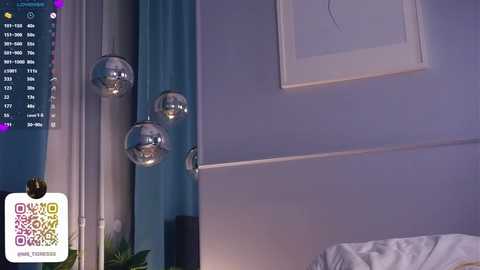 Media: A video of a modern bedroom featuring light blue walls, a white headboard, and three metallic spherical pendant lights. A digital clock with a QR code is visible on the left.