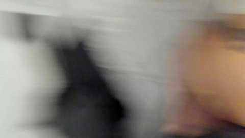 Media: A blurred video shows a person, likely male, with a light skin tone, partially visible. The background is indistinct, with a possible black object or shadow. The image appears grainy and out of focus.