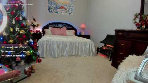 Media: Video of a cozy bedroom with a Christmas tree, white bed with ruffled skirt, and a dark wooden dresser.