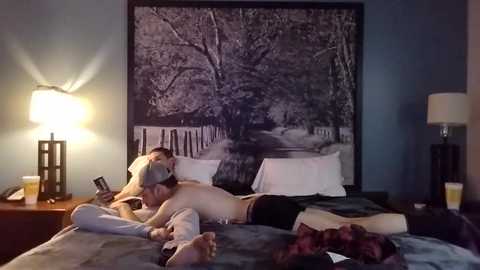 Media: Video of a man and woman lying on a bed, engaged in oral sex, in a dimly-lit bedroom with a black-and-white tree mural on the wall.