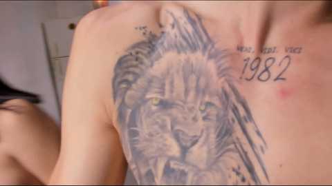 Media: Video of a tattoo on a man's back depicting a lion with \"HODOR F**K YES 1982\" written on it. The background shows a blurred room with a door.