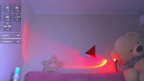 Video of a cozy, dimly lit room with a plush teddy bear, a star-shaped ornament, and a red triangular decoration on a pink couch under a soft, ambient light.