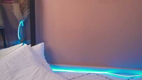 Media: A video of a minimalist bedroom with a white bed and soft lighting, featuring a glowing neon blue light strip under the bed. The room has a neutral, beige wall.