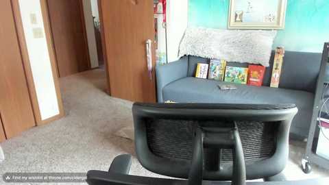 Media: Video of a modern office chair facing a cozy living room with a blue sofa, bookshelves, and framed artwork.