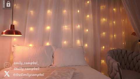 Video of a cozy, warmly lit bedroom with white curtains, a white bed, and a vintage-style lamp; text reads \"campbell@campbellcampebell.\