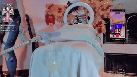 Media: Video of a person's arm, dressed in a white robe, being massaged with a cream-like substance by a robotic arm in a spa setting. Background shows a large, ornate mirror and a colorful, floral mural.