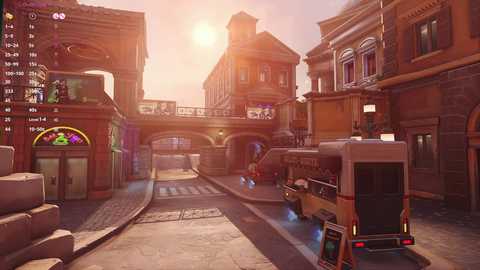 Media: A CGI screenshot of a bustling medieval city street with a bus, colorful buildings, arches, and a glowing neon sign. The scene exudes a warm, golden glow from the setting sun.