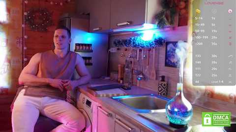 Media: Video of a muscular, shirtless man with short hair in a modern, colorful kitchen with a sink, utensils, and decorative items.