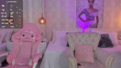 Media: Video of a pink gaming chair and beige armchair in a dimly-lit bedroom with purple lighting, featuring a woman in a black dress and a hanging pendant light.