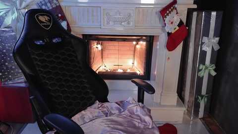 Media: A video of a cozy living room with a lit fireplace, a black gaming chair, and Christmas decorations including a red Santa hat and a green bow.