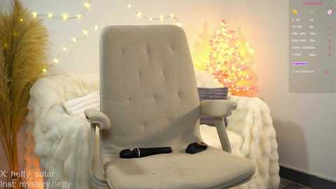 Media: Video of a beige ergonomic chair in a cozy, softly lit room with a lit Christmas tree, fluffy white blanket, and string lights on the wall.