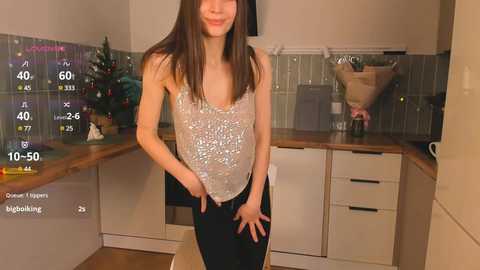 Media: Video of a slender Asian woman in a sequined top and tight black pants in a modern kitchen.