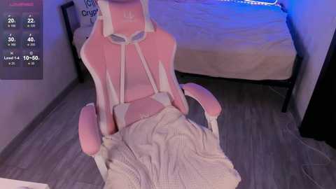 Video of a pink gaming chair with a white blanket, in a dimly-lit room with a bed and blue light.