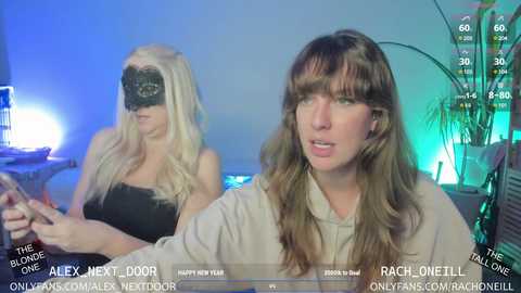 Media: A video of two women in a virtual reality setup, one wearing a black blindfold and the other with long brown hair, both in a dimly lit room with blue and green lighting.