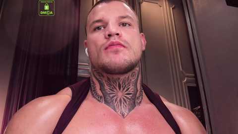 Media: Video of a muscular man with short, light brown hair and a shaved head, wearing a black tank top, showcasing intricate tattoos on his chest and neck.