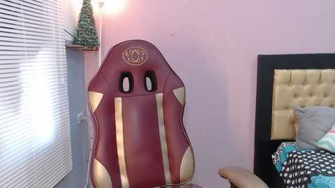 Media: Video of a plush, purple gaming chair with gold accents and black eye holes, positioned in a pastel pink room with a bed and window blinds.