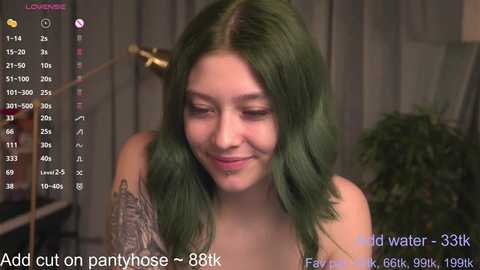 Media: Video of a young woman with shoulder-length, vibrant green hair, wearing a sleeveless top, smiling. The background features a blurred, indoor setting with gray curtains and a potted plant. Text overlays indicate \"Add cut on pantyhose\" and \"Follower count: 38k.\