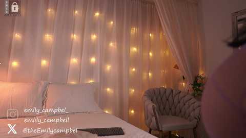 Video of a cozy bedroom with white curtains, fairy lights, a plush bed, and a tufted chair, capturing a serene, romantic atmosphere.