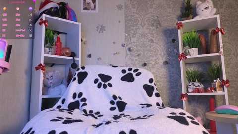 Video of a cozy, themed bedroom with white paw-print duvet, cat-shaped pillows, and white shelves adorned with Christmas ornaments.