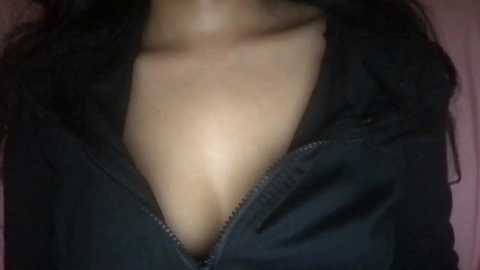 Media: Video of a woman's chest, showing cleavage in a black hoodie, with visible skin tone and hint of a collarbone.