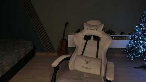 Media: A video of a white gaming chair, a guitar, and a decorated Christmas tree in a dimly lit room with wooden floors.