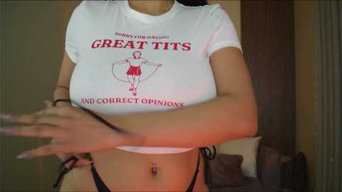 Media: Video of a woman wearing a tight white crop top with a red drawing of a woman lifting weights, and black bikini bottoms.