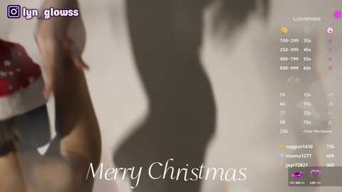 Media: Video of a nude woman's silhouette with a Christmas-themed background, featuring a red and white Santa hat. Text reads \"Merry Christmas.\