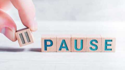 Media: Video of a light-skinned hand holding a wooden block with the letter \"P\" in blue, placed next to a block spelling \"PAUSE\" in the same wooden style, on a light wooden floor.