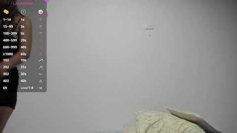 Media: A video of a light-skinned person holding a smartphone with a white wall in the background. The screen shows a camera app with a grid and a shutter button. The room has a simple, minimalistic design with a beige pillow on a bed.