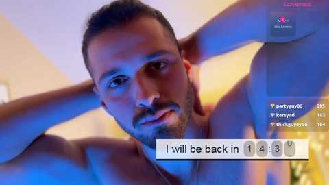 Media: A video of a shirtless, muscular man with short dark hair, a beard, and intense expression, taken from a low angle. Background is blurred with blue lighting. Text overlay reads, \"I will be back in 1 hour 14 minutes.\