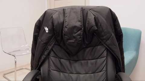 Media: A video of a black Nike gym bag with a white logo on a white wall, featuring a clear acrylic chair and a light blue upholstered chair in the background.