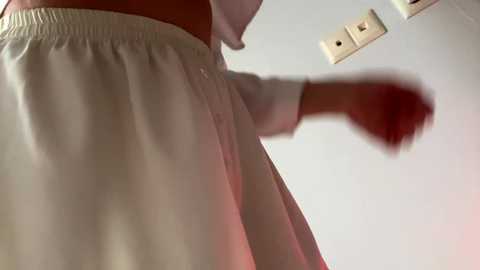 Video of a person in white clothes, possibly a nurse, throwing a red object, likely a ball or toy, against a plain white background.