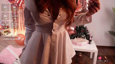 Media: A video capturing a close-up of a woman with long, auburn hair in a pink dress, hugging a smaller person, in a festive room with pink balloons, a white table, and a cake.