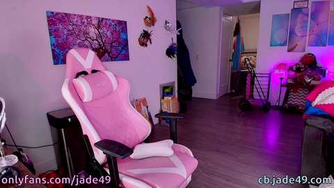 Media: A video of a cozy, dimly-lit living room featuring a pink gaming chair, colorful artwork, and a small table with a lamp.