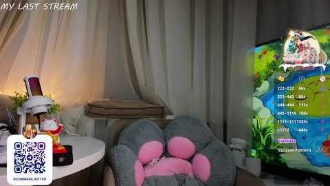 Media: A video shows a cozy, dimly lit room with a large gray teddy bear and a gaming setup featuring a screen displaying a colorful game interface.