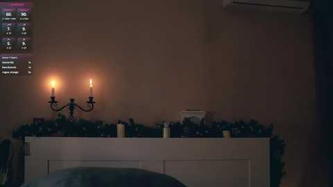 Media: A dimly lit video of a cozy, decorated fireplace with two lit candles, a garland, and various objects, set against a beige wall.