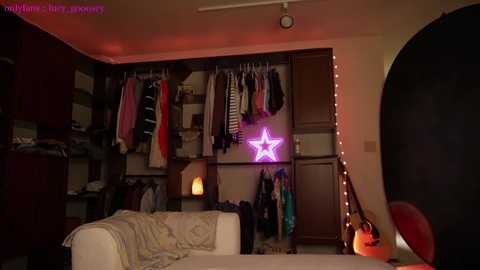 Media: A video of a cozy, dimly lit bedroom with a star-shaped neon light, hanging clothes, a plush couch, and fairy lights.