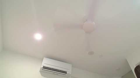 Media: A video showing a dimly lit ceiling with a large air conditioner, a fan, and a light bulb emitting a bright glare, creating a hazy, foggy atmosphere.