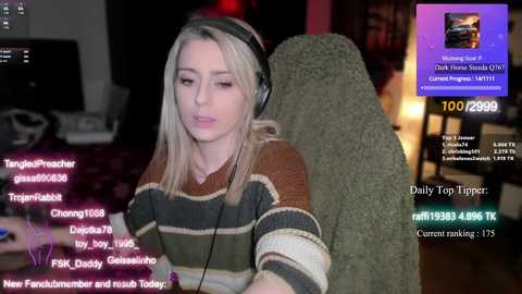 Media: Video of a young, fair-skinned woman with blonde hair, wearing headphones, in a dimly lit room. Live streaming overlay shows chat messages and donation amounts.