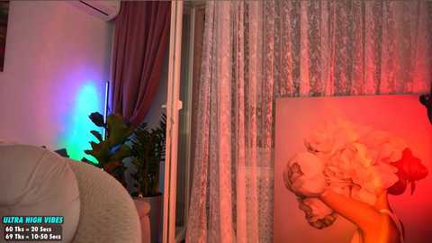 Media: Video of a cozy living room with a large Marilyn Monroe poster on the wall, a potted plant, and a soft, multicolored light glow.