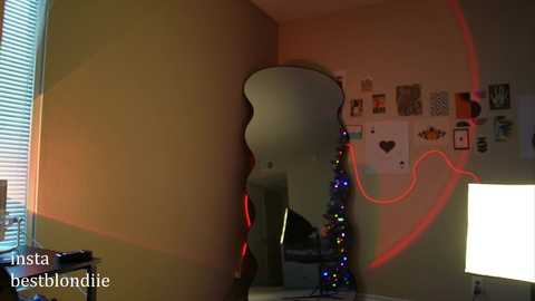 Media: Video of a bedroom with a large, reflective guitar-shaped mirror casting shadows on beige walls. The room is illuminated by red and blue LED lights, creating a playful, artsy ambiance.