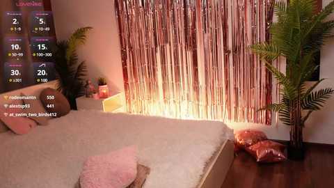 Media: A video of a cozy, dimly-lit room with a white bed, fluffy pink pillow, and metallic rose garland backdrop.